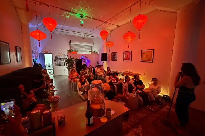 Comedy night at Bu Tea Den: a packed lounge under red lanterns, the comic on the mic